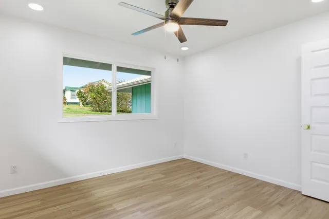 an empty room with wooden floor fan and windows