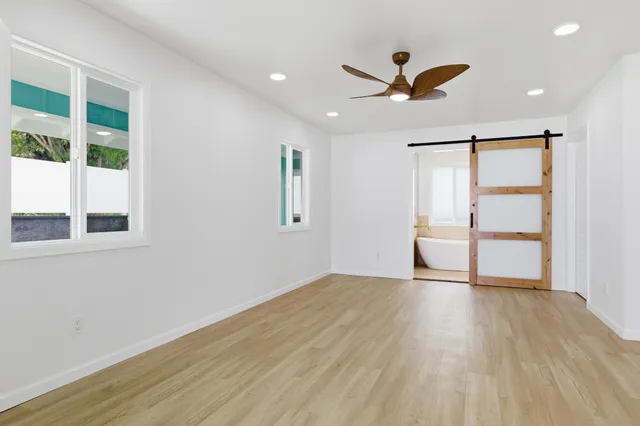 a view of empty room with wooden floor and fan