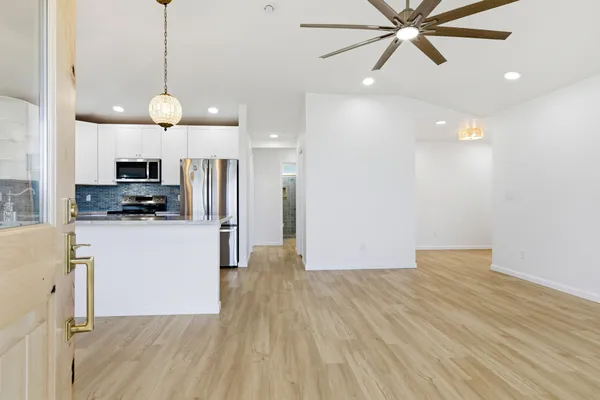 a view of a kitchen with a sink a refrigerator a ceiling fan and wooden floor