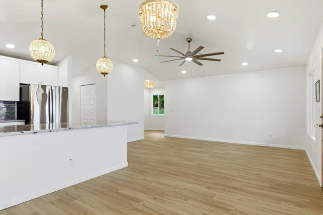 a view of an empty room with a window and kitchen view
