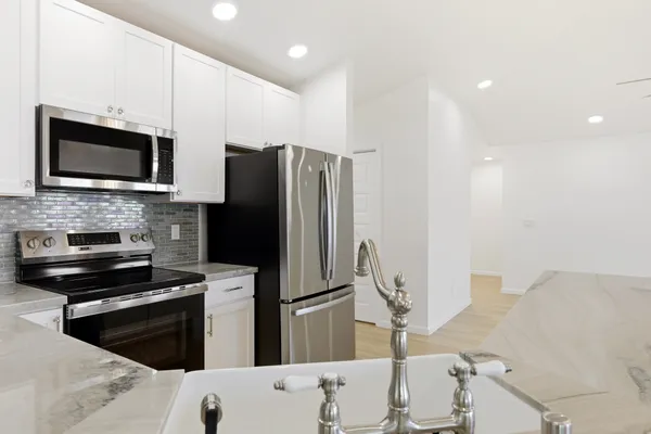 a kitchen with granite countertop a refrigerator and a stove top oven