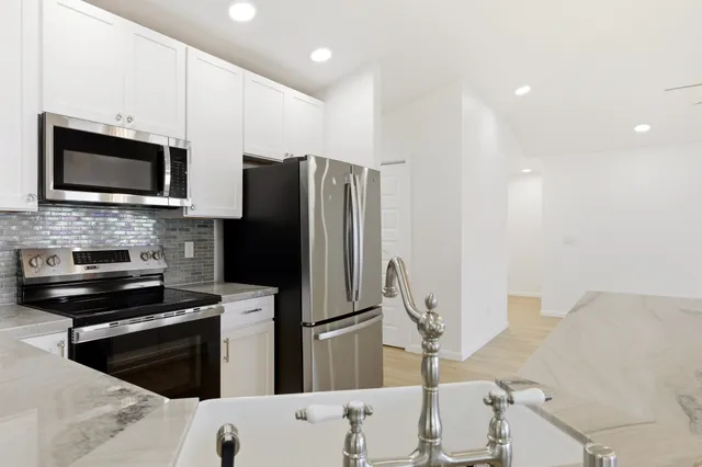 a kitchen with granite countertop a refrigerator and a stove top oven