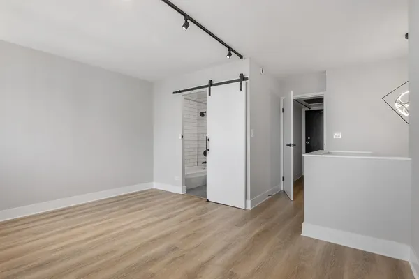 a view of an empty room with wooden floor and a window