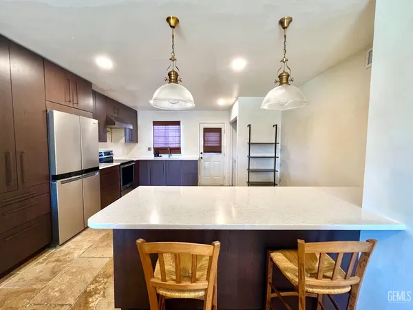 a living room with stainless steel appliances furniture a rug and a view of kitchen