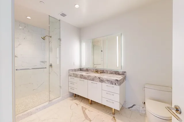 a bathroom with a granite countertop sink a toilet and a shower