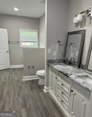 a spacious bathroom with a granite countertop sink a toilet and a mirror