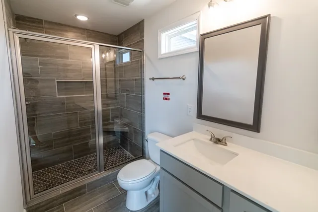 a bathroom with a shower sink vanity mirror and toilet