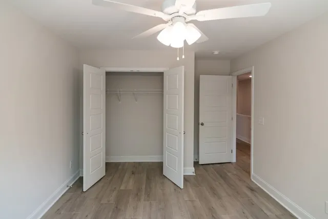 an empty room with wooden floor and a ceiling fan