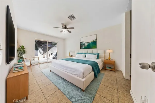 a spacious bedroom with a bed a couch and a flat tv screen