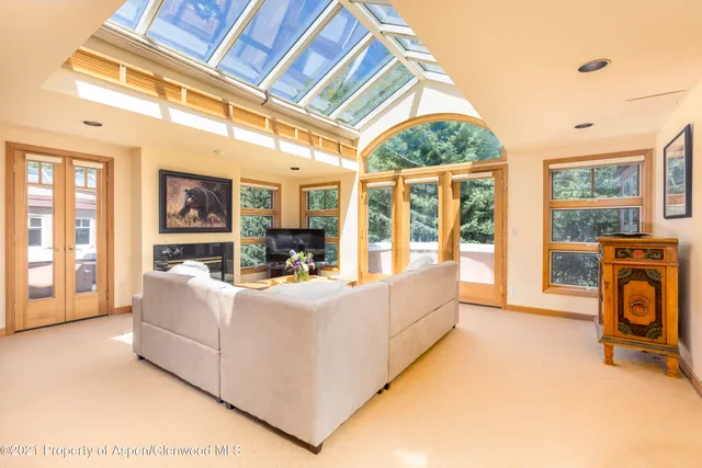 a living room with furniture a flat screen tv and floor to ceiling window