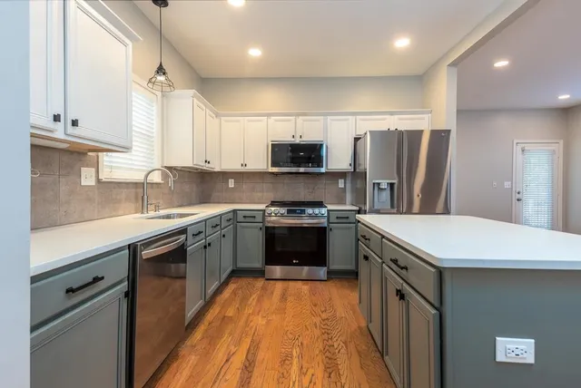 a large kitchen with stainless steel appliances granite countertop a stove top oven a sink and a refrigerator