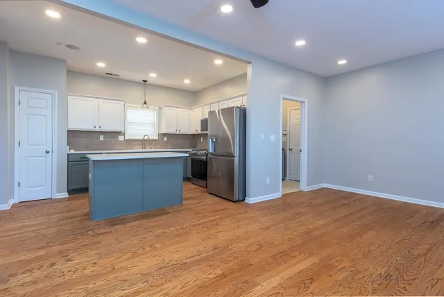 a kitchen with stainless steel appliances kitchen island granite countertop a refrigerator and a stove top oven