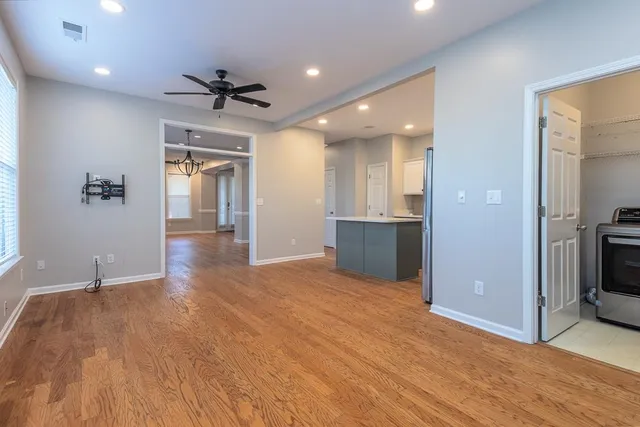 an empty room with wooden floor and a kitchen