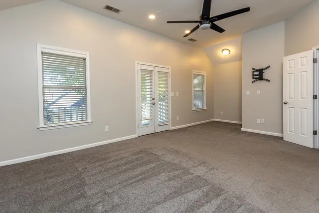 en empty room with windows and ceiling fan