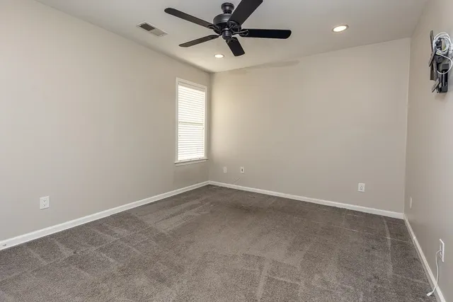 an empty room with windows and fan