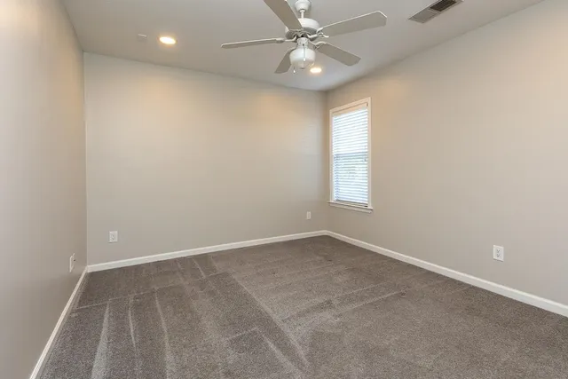 an empty room with windows and fan