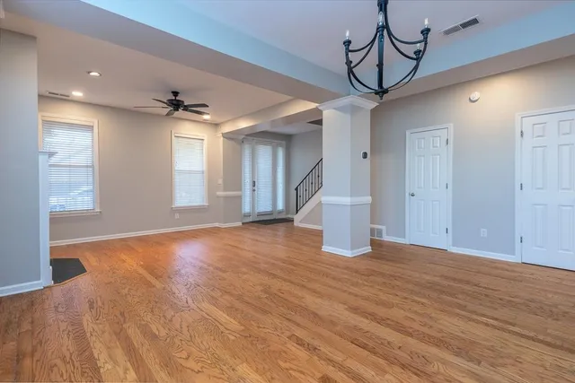 a view of empty room with wooden floor and fan