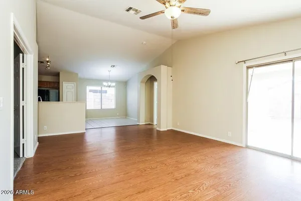 an empty room with wooden floor and a ceiling fan