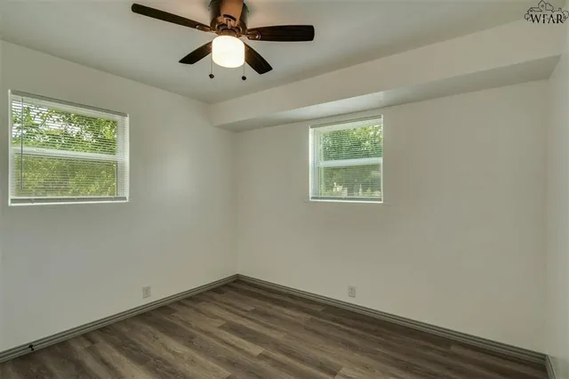 a view of empty room with wooden floor and fan