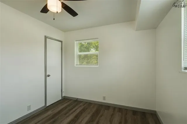 an empty room with a hardwood and ceiling fan