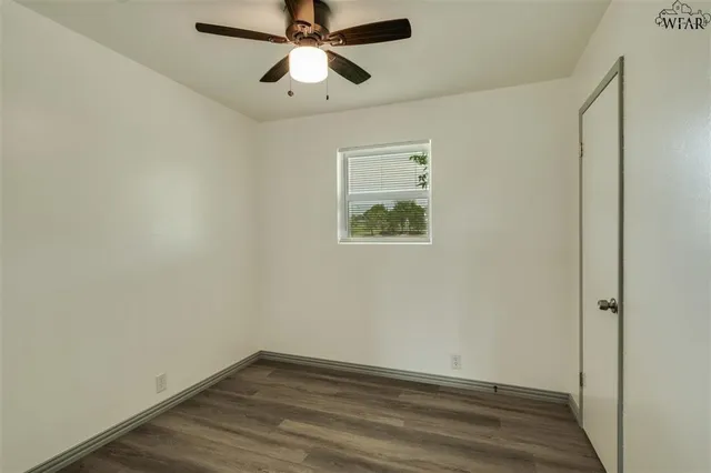 an empty room with wooden floor and ceiling fan