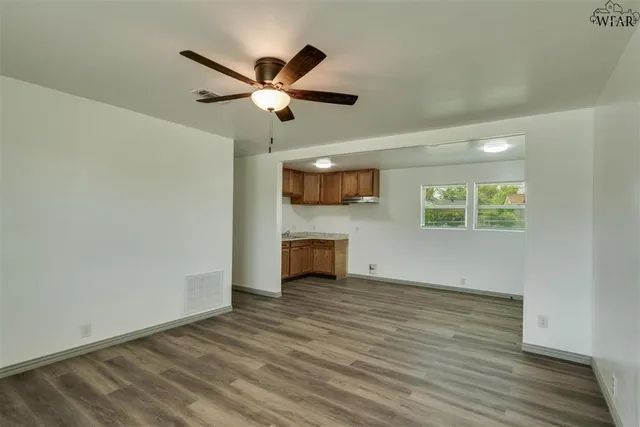 a view of an empty room with a window and wooden floor