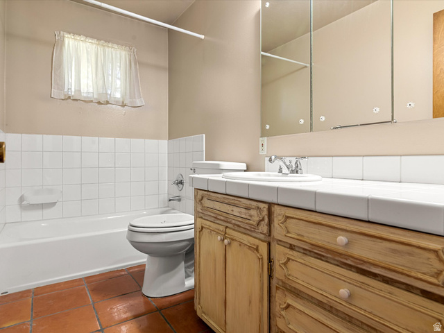 15680 North Beaver Dam Road Collinston, UT 84306 - Photo 26 of 49 Bathroom featuring a vanity with an integrated sink, a three-section medicine cabinet, a full-size bathtub, white subway tile wainscoting, and terracotta tile flooring