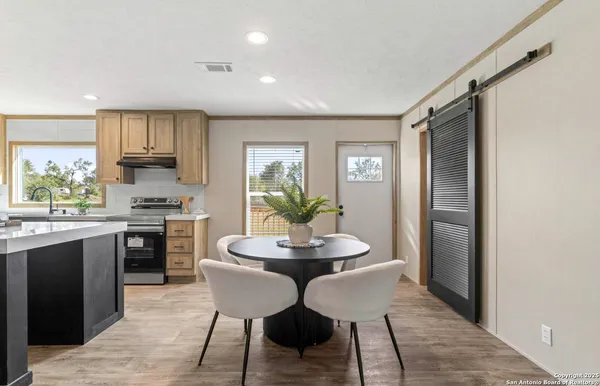 a kitchen with stainless steel appliances granite countertop a stove top oven a sink a refrigerator with a dining table and chairs