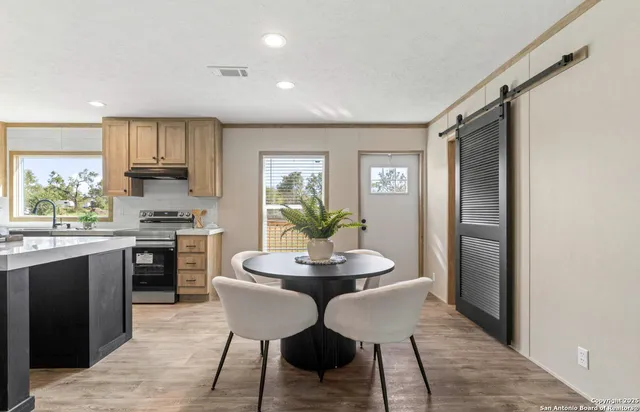 a kitchen with stainless steel appliances granite countertop a stove top oven a sink a refrigerator with a dining table and chairs