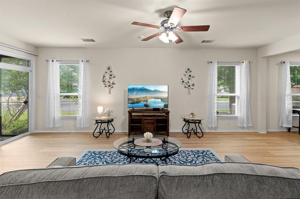 109 Providence Street Georgetown, TX 78633 - Photo 10 of 31 Open-concept living area featuring light wood-finish flooring, multiple windows with blinds, a sliding glass door to exterior, and a ceiling fan with integrated lighting