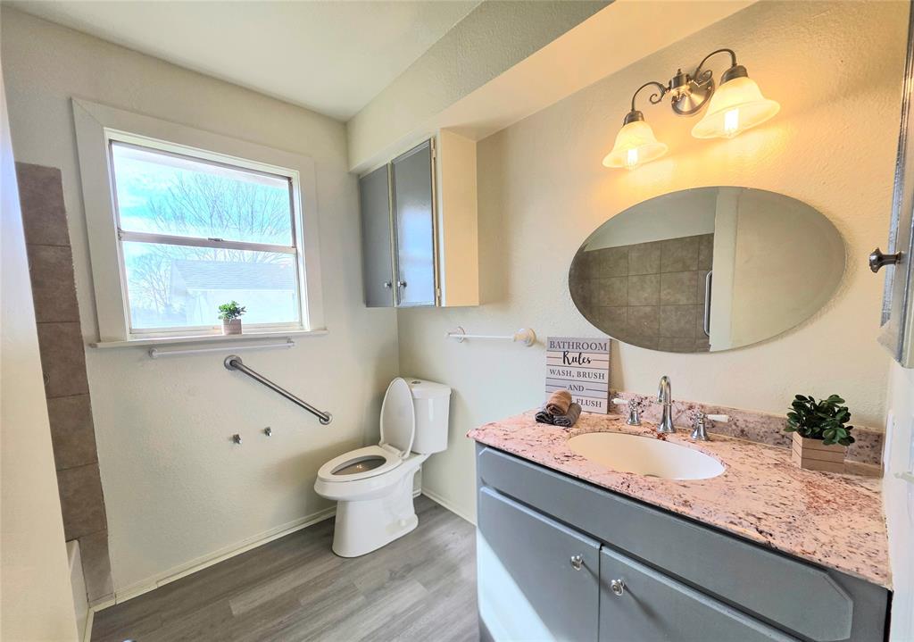 406 East Brazos Street Groesbeck, TX 76642 - Photo 8 of 29 a bathroom with a granite countertop toilet a sink and a mirror