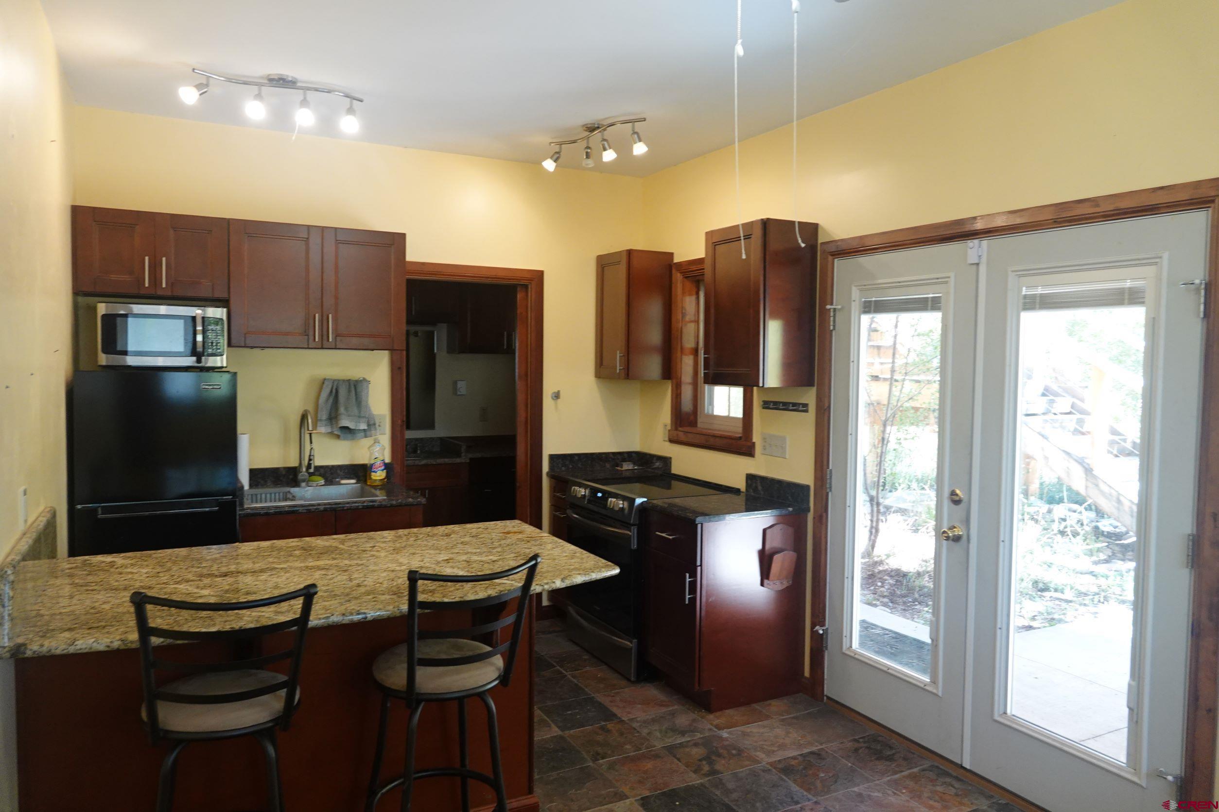 15835 Black Bridge Road Paonia, CO 81428 - Photo 30 of 35 a kitchen with a table chairs refrigerator and cabinets