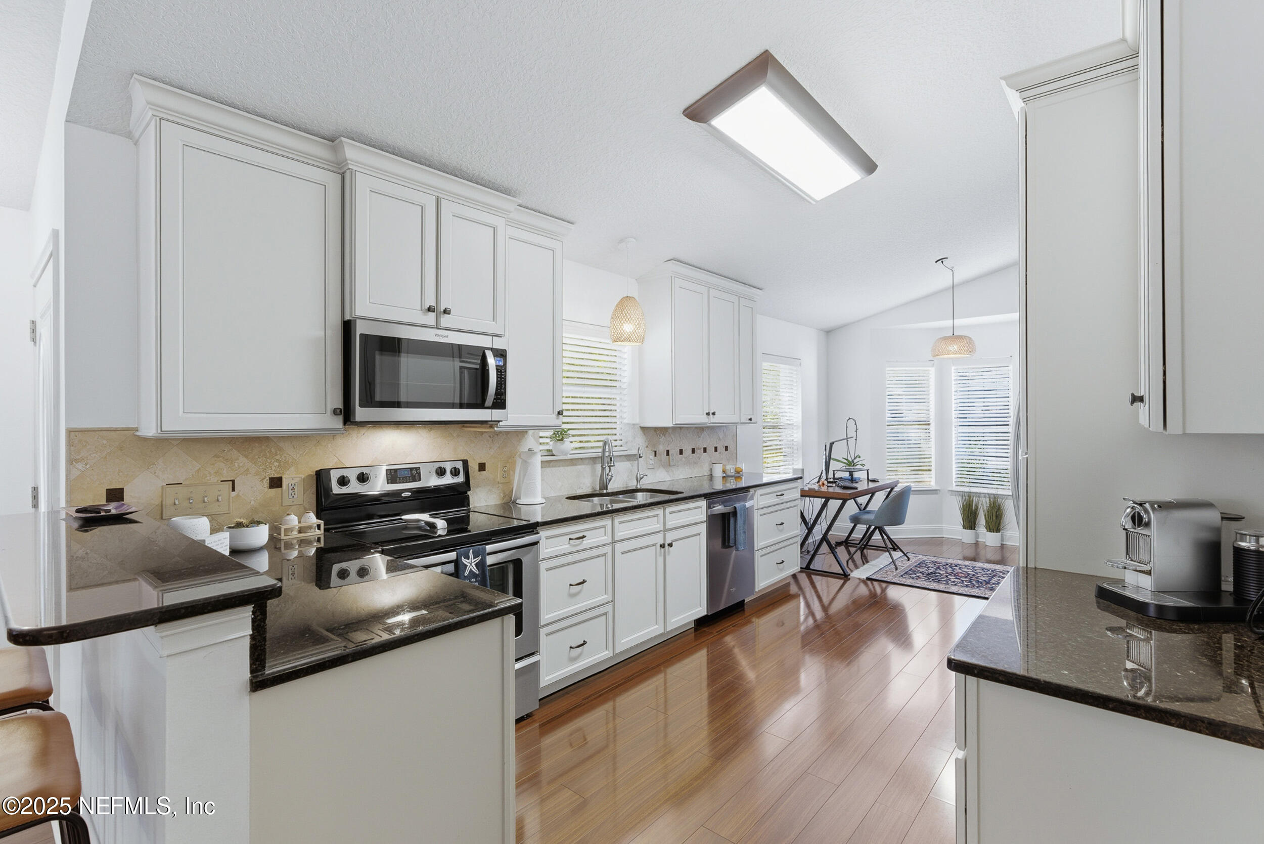 128 Seminole Road, Unit 11 Atlantic Beach, FL 32233 - Photo 5 of 26 a kitchen with stainless steel appliances granite countertop a stove top oven a sink a dining table and chairs with wooden floor
