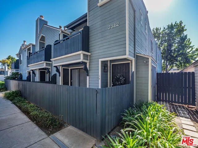 a view of a house with plants and wooden fence