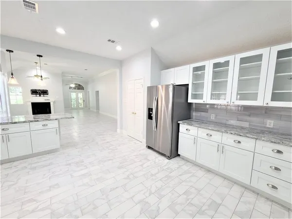 a kitchen with granite countertop a refrigerator and white cabinets