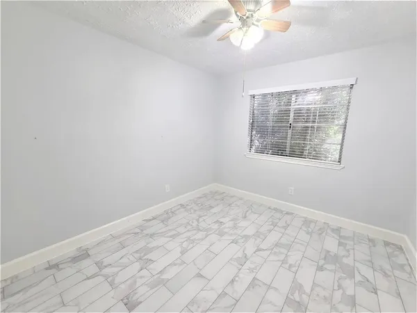 an empty room with a chandelier fan and windows