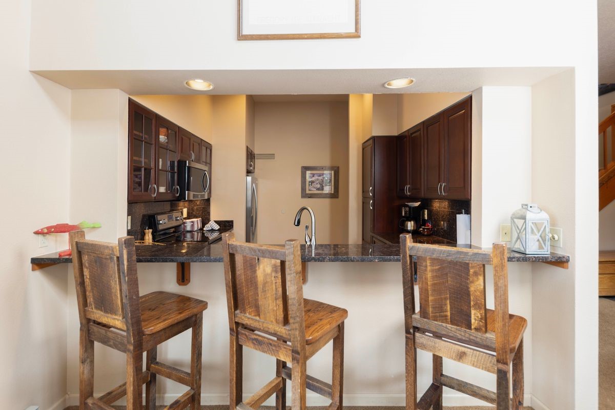 240 Tennis Club Road, Unit 1664 Keystone, CO 80435 - Photo 7 of 26 Kitchen featuring dark brown cabinetry, tasteful backsplash, kitchen peninsula, and appliances with stainless steel finishes