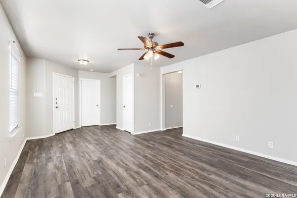 a view of a room with wooden floor and a ceiling fan