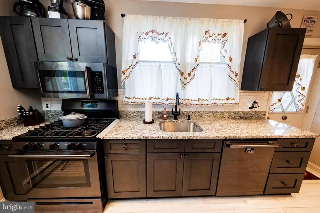 a kitchen with granite countertop a sink stove and cabinets