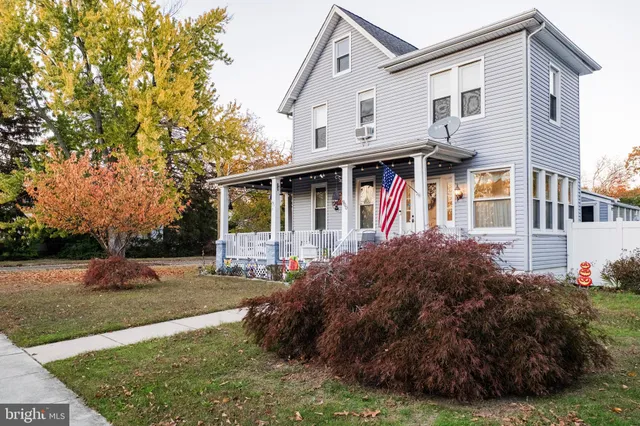 a view of a white house next to a yard with big trees