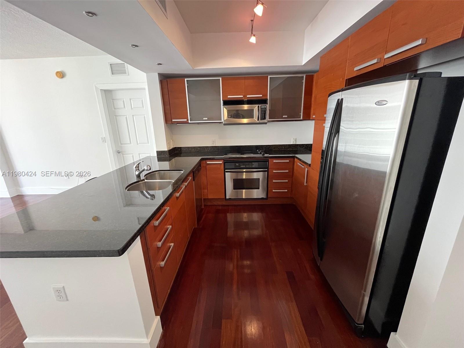 2030 Douglas Road, Unit 610 Coral Gables, FL 33134 - Photo 2 of 19 a kitchen with stainless steel appliances granite countertop a refrigerator a stove and a sink with wooden floors