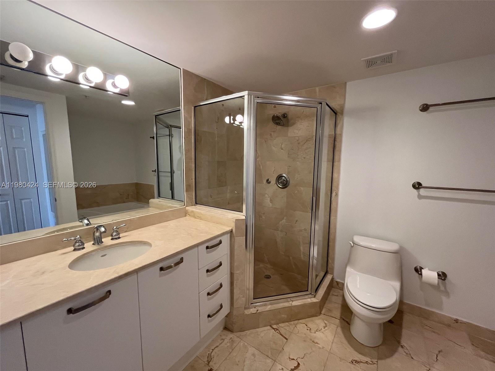 2030 Douglas Road, Unit 610 Coral Gables, FL 33134 - Photo 9 of 19 a bathroom with a toilet a sink a mirror a vanity and shower