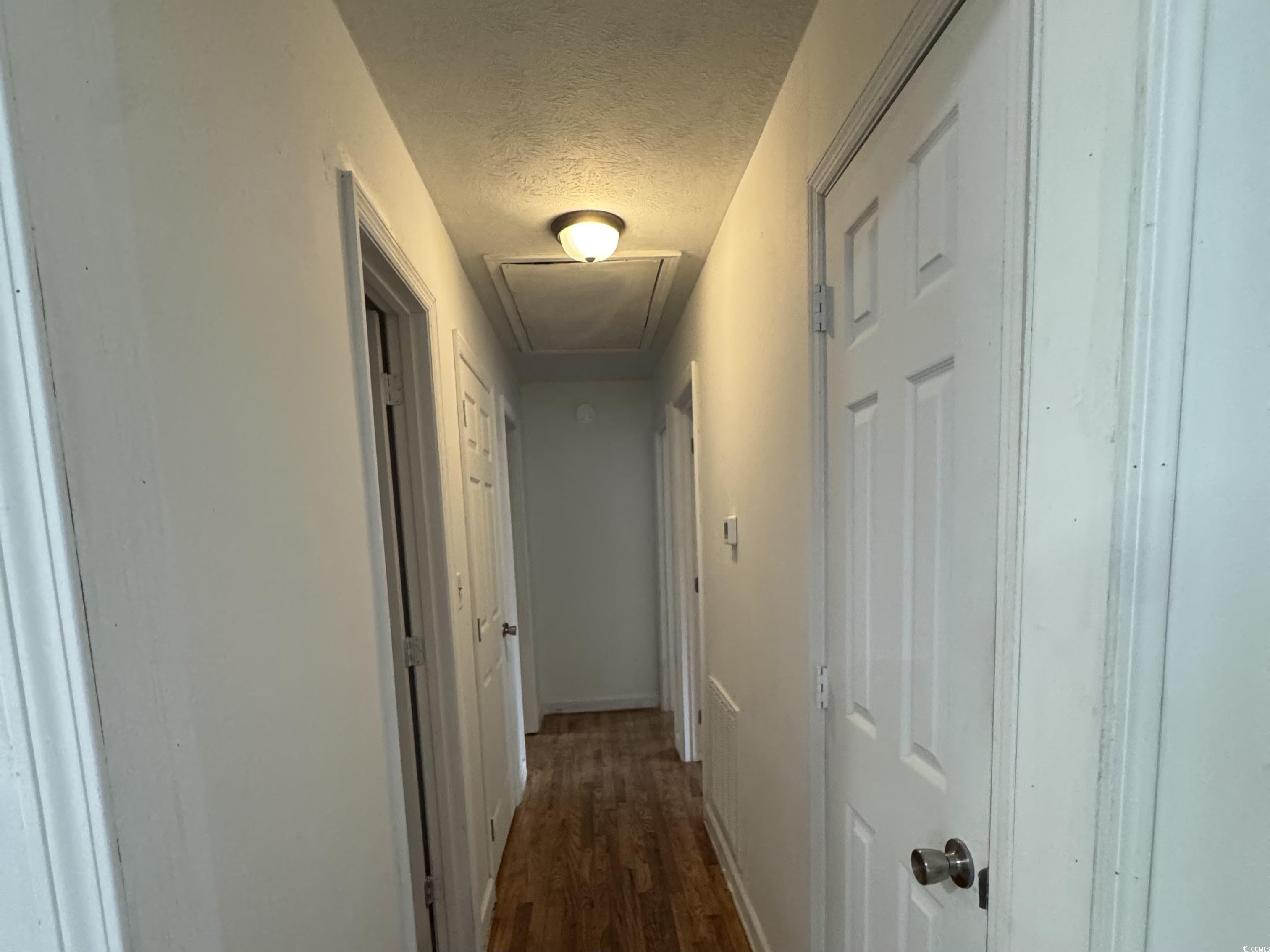 1127 State Rd S-17-640 Dillon, SC 29536 - Photo 15 of 26 Corridor with a textured ceiling, dark wood-style flooring, and attic access