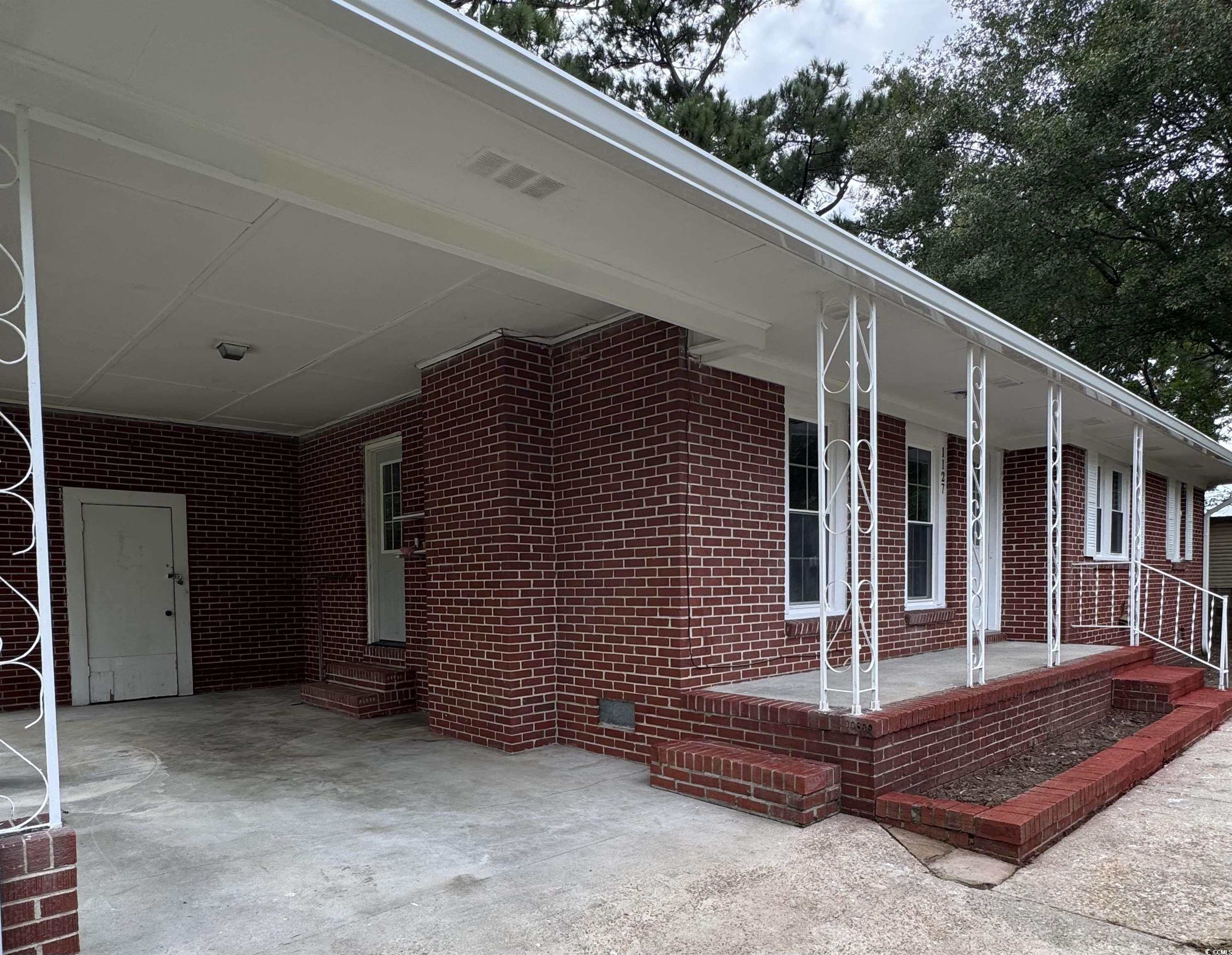 1127 State Rd S-17-640 Dillon, SC 29536 - Photo 6 of 26 View of home's exterior featuring brick siding, covered porch, a carport, and entry steps