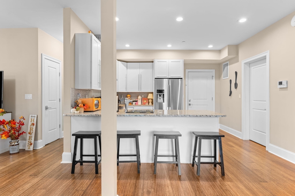 380 West Broadway, Unit 401 Boston, MA 02127 - Photo 4 of 25 a kitchen with stainless steel appliances granite countertop a table chairs refrigerator and sink