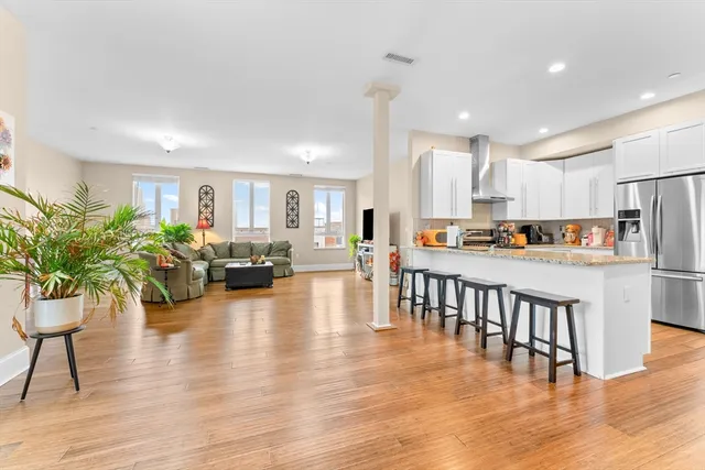 a living room with furniture and a dining table with wooden floor