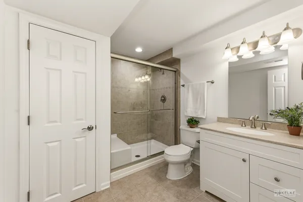 a spacious bathroom with a double vanity sink toilet mirror and shower