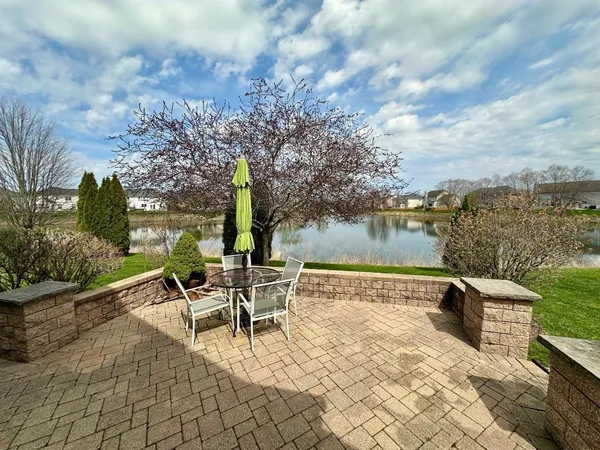 a view of a lake with table and chairs and potted plants