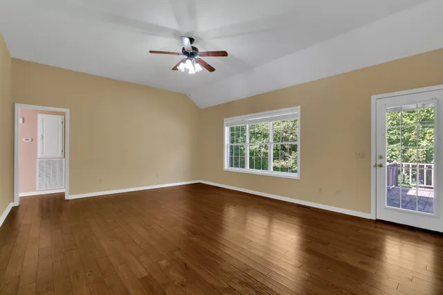 a view of an empty room with wooden floor and a window