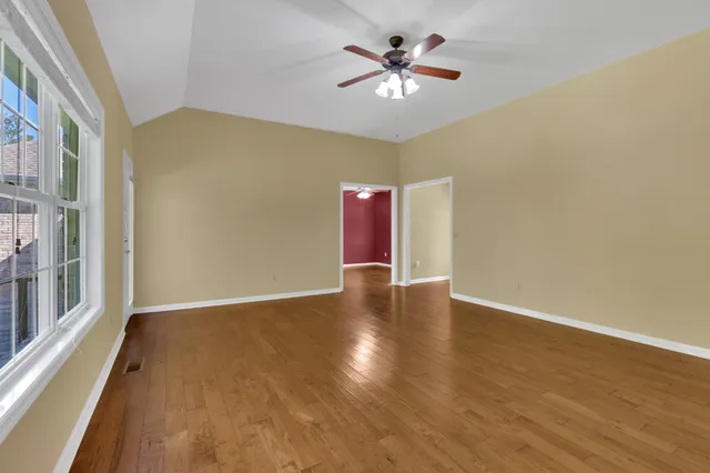a view of an empty room with a window and wooden floor
